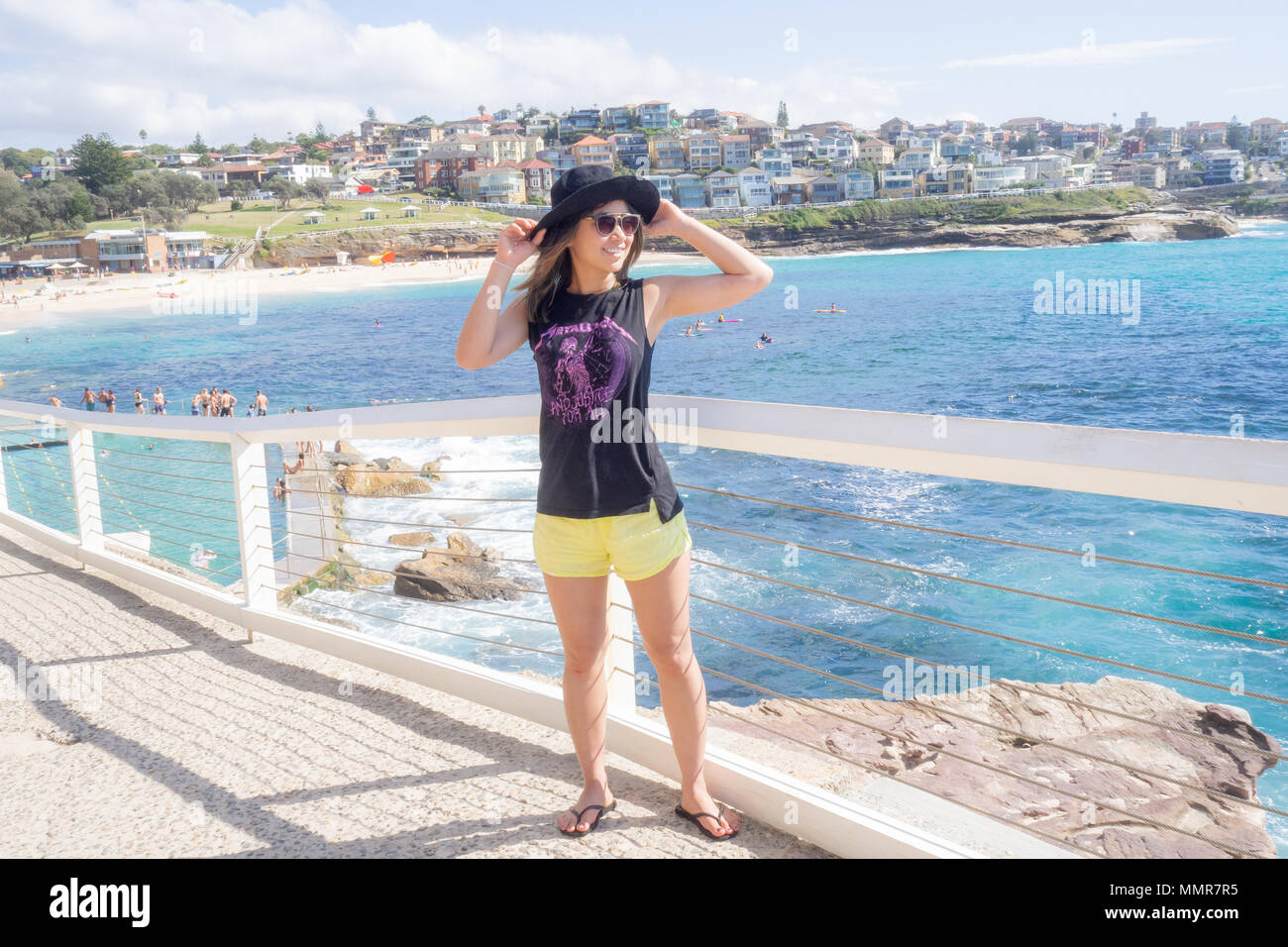 Jeune femme avec chapeau et des lunettes à pied par la piscine publique à Bronte beach à Sydney Australie Banque D'Images