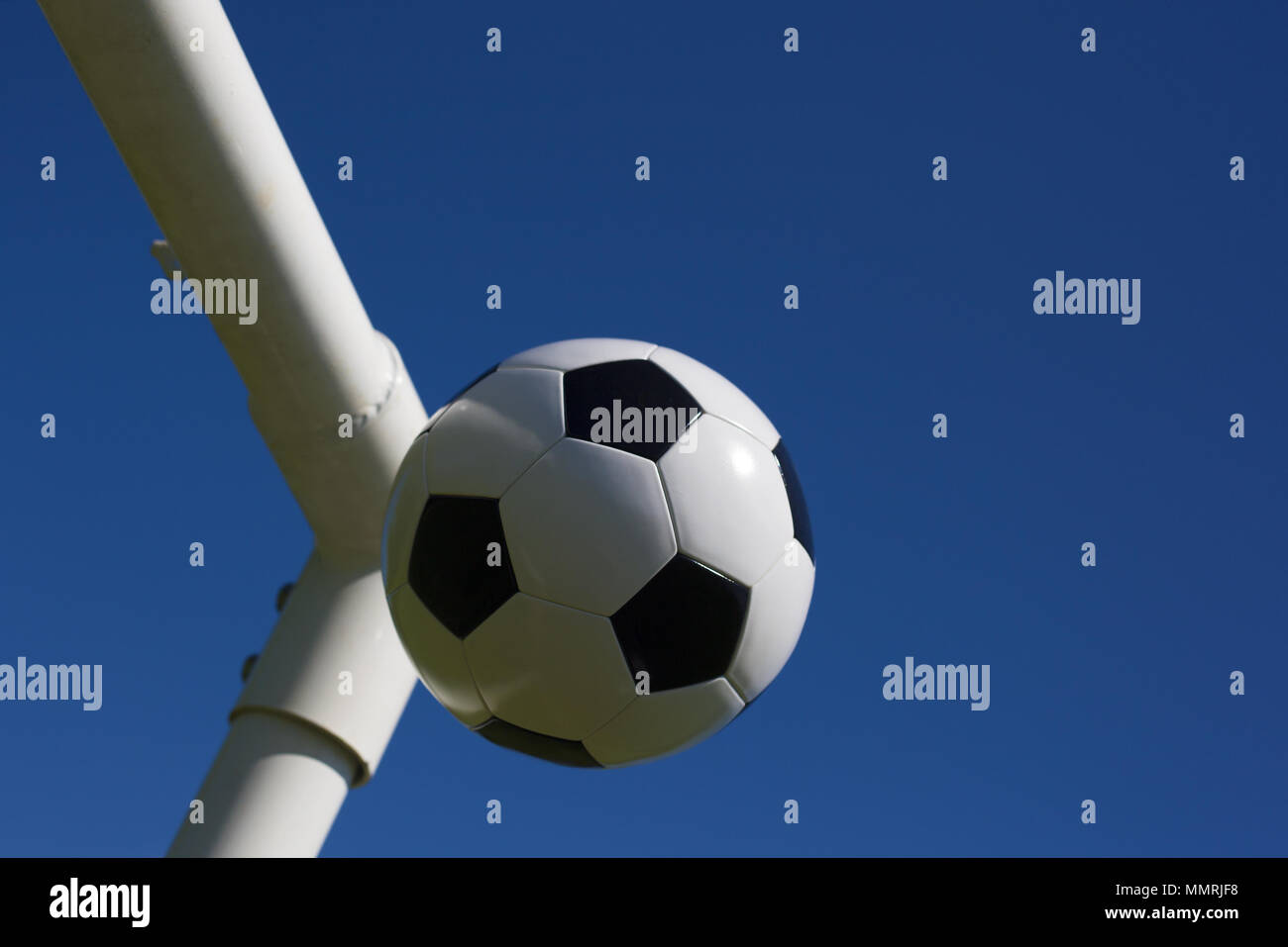 Un football en cuir noir et blanc à la croix des poteaux de but Banque D'Images