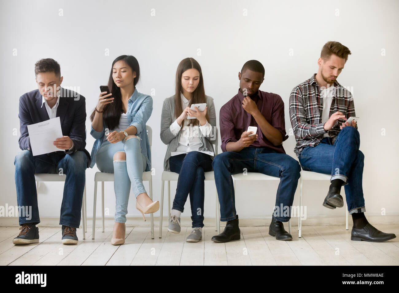 Diverses personnes en attente dans la file d'attente millénaire holding reprend en utilisant Banque D'Images