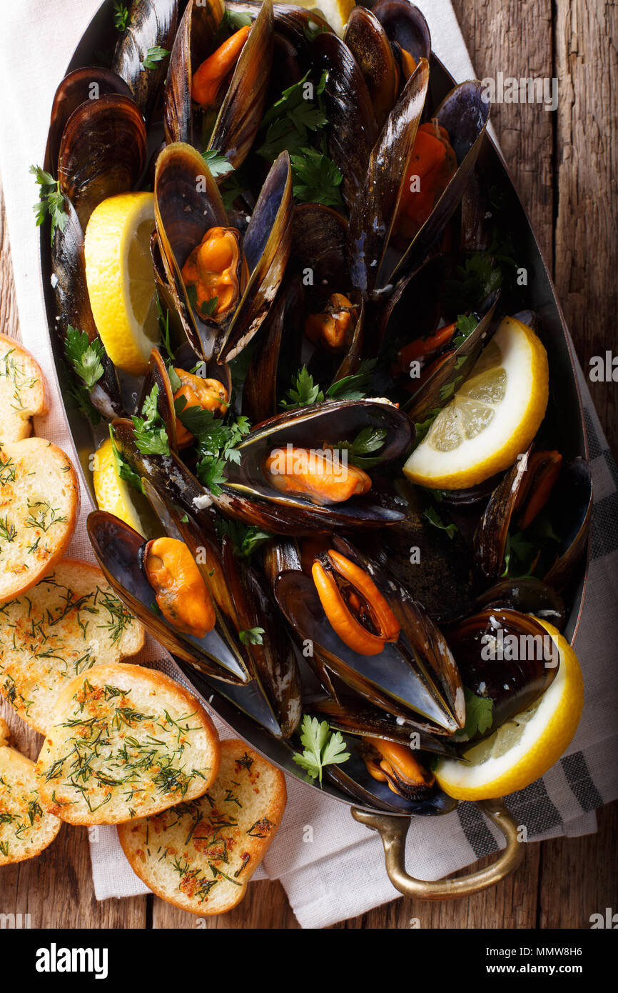 Moules à la française citron, le persil et l'ail close-up dans une marmite en cuivre et de grillé sur la table. Haut Vertical Vue de dessus Banque D'Images