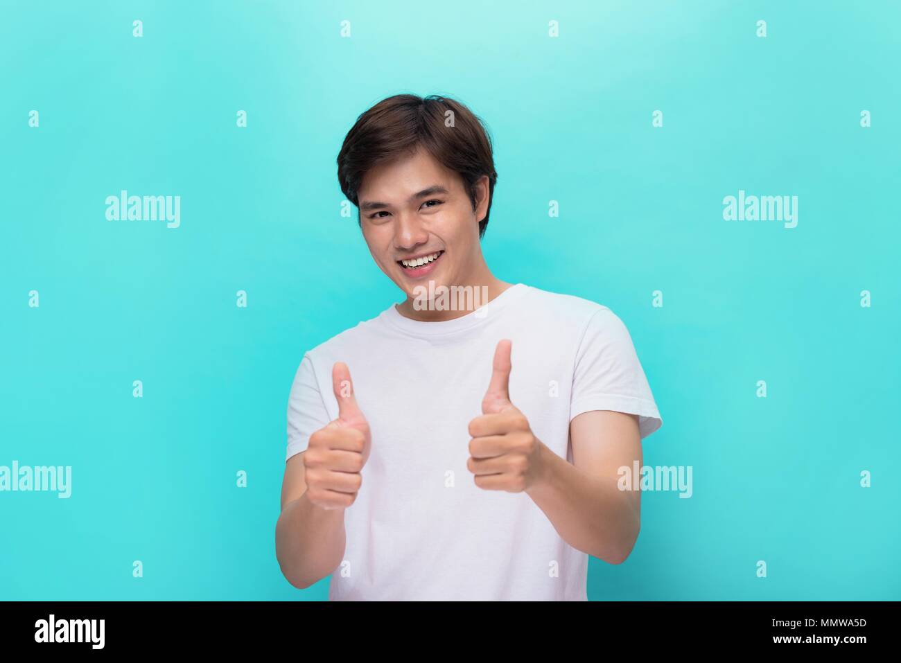 Portrait of a young man showing Thumbs up isolé sur mur gris geste Banque D'Images