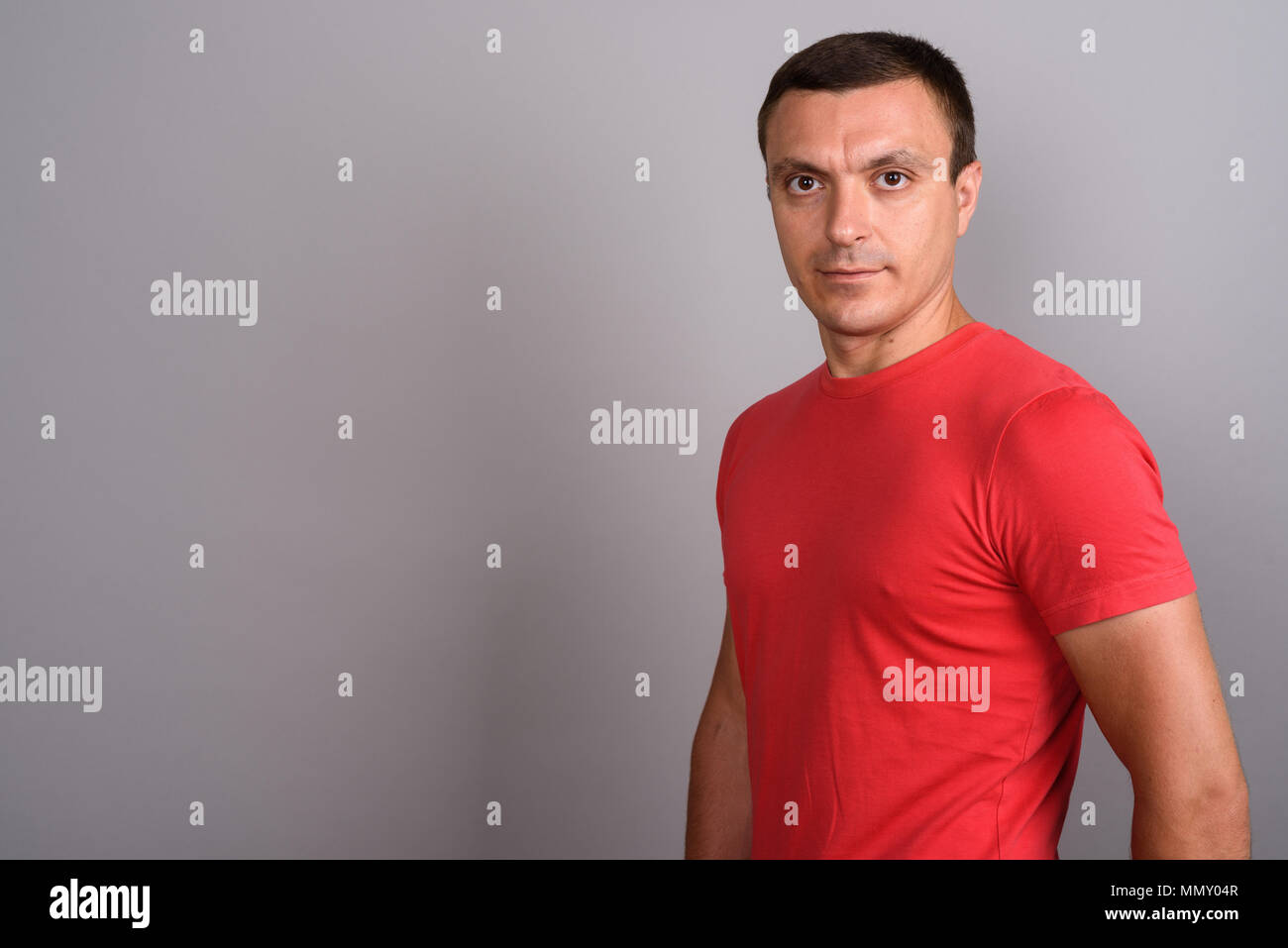 Homme portant un tee-shirt rouge à l'arrière-plan gris Banque D'Images