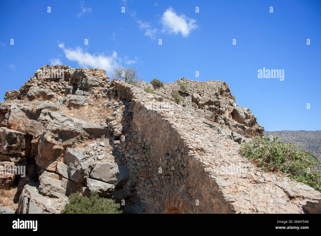 Ancienne forteresse ruines sur l'île de Spinalonga, la Crète, Grèce. Vue panoramique, colline branlante sèche, vert et bleu cactus, ciel nuageux Banque D'Images