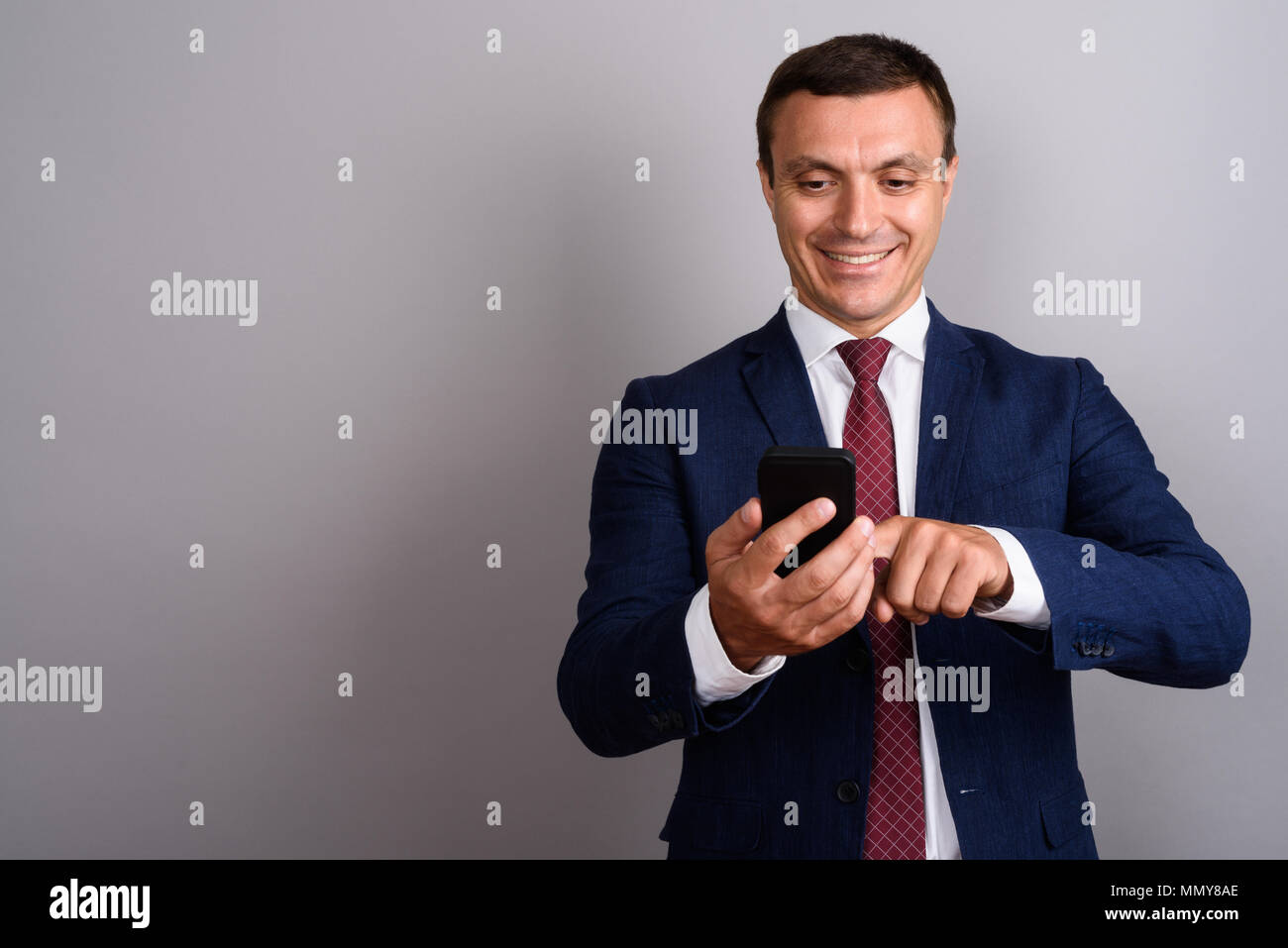 Businessman wearing suit lors de l'utilisation de téléphone mobile contre b gris Banque D'Images