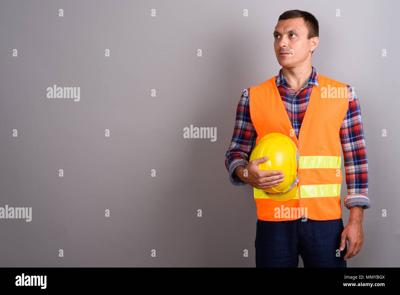 Travailleur de la construction de l'homme contre l'arrière-plan gris Banque D'Images