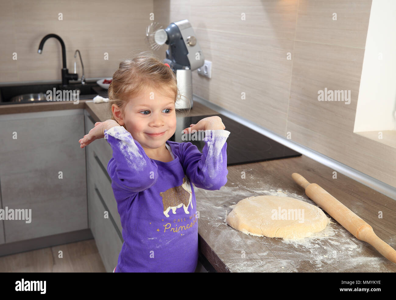 Petite fille joyeuse en cuisine. Les enfants premiers pas dans la cuisine. Banque D'Images