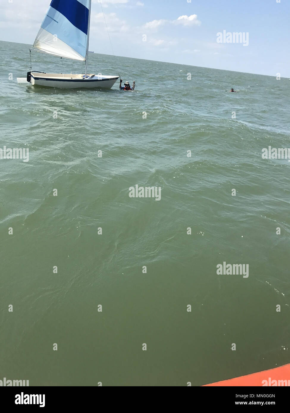 Un homme de 70 ans et ses 34 ans, fils d'attendre pour l'assistance de la Garde côtière canadienne après re-redressement leur voilier chaviré dans l'eau au large de Cape Charles, Virginie, le 5 août 2017. Une Garde côtière 29 pied-Boat-Small Réponse de l'équipage de gare Cape Charles est arrivé sur les lieux, tiré les hommes de l'eau, a pris le voilier en remorque et les a amenés à terre en toute sécurité. (U.S. Photo de la Garde côtière du Maître de 2e classe Francisco Garcia/libérés) Banque D'Images