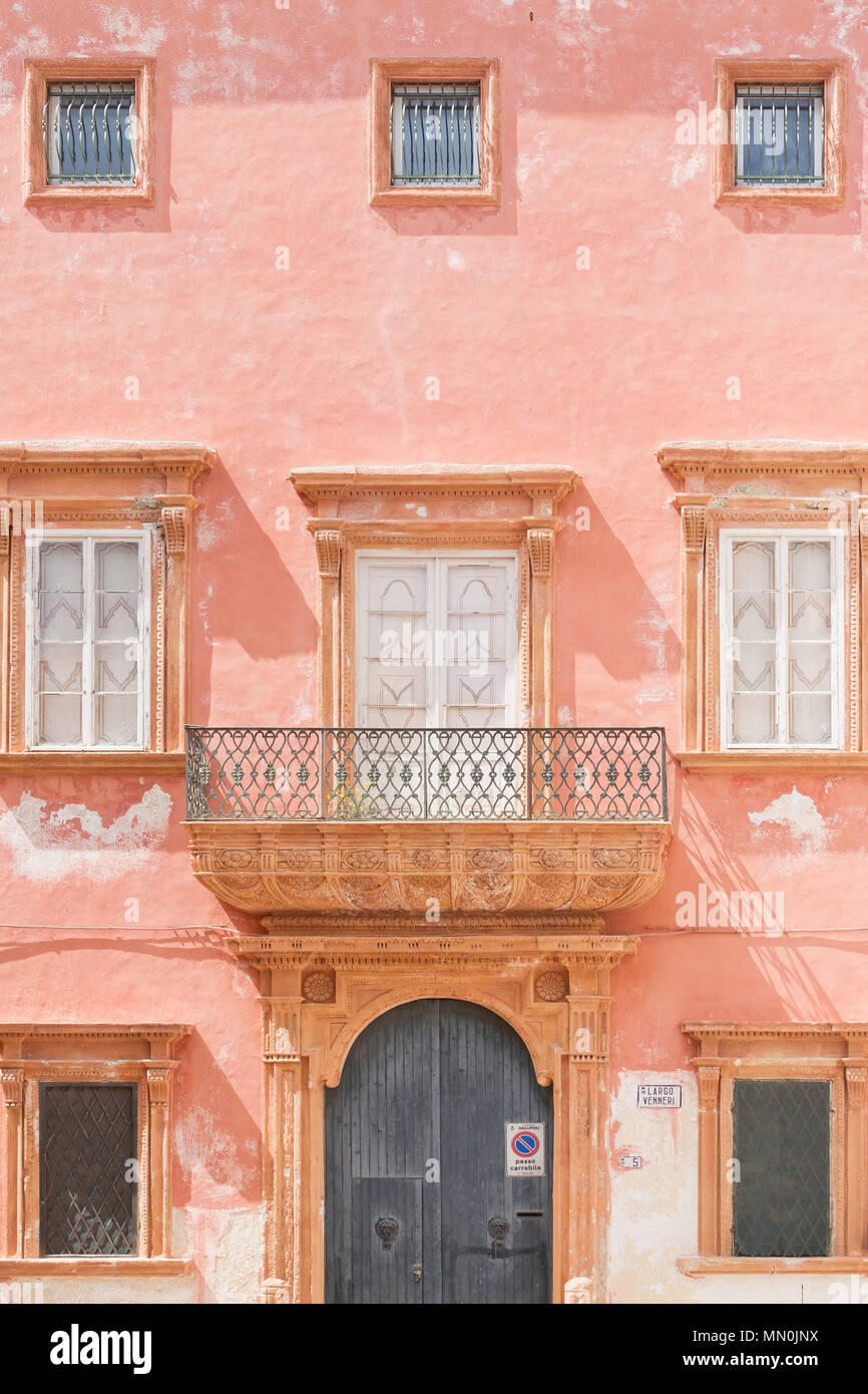 Gallipoli, Pouilles, Italie - une façade rose avec une porte de grange et plusieurs fenêtres Banque D'Images