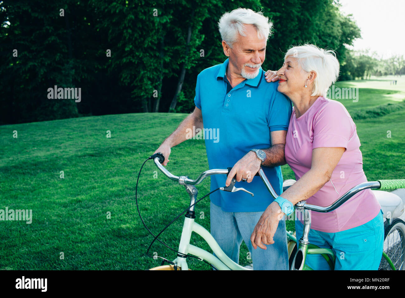 Mature couple enjoying day out sur leur bicyclette. vieille femme embrasse son mari alors que le repos actif dans le parc Banque D'Images