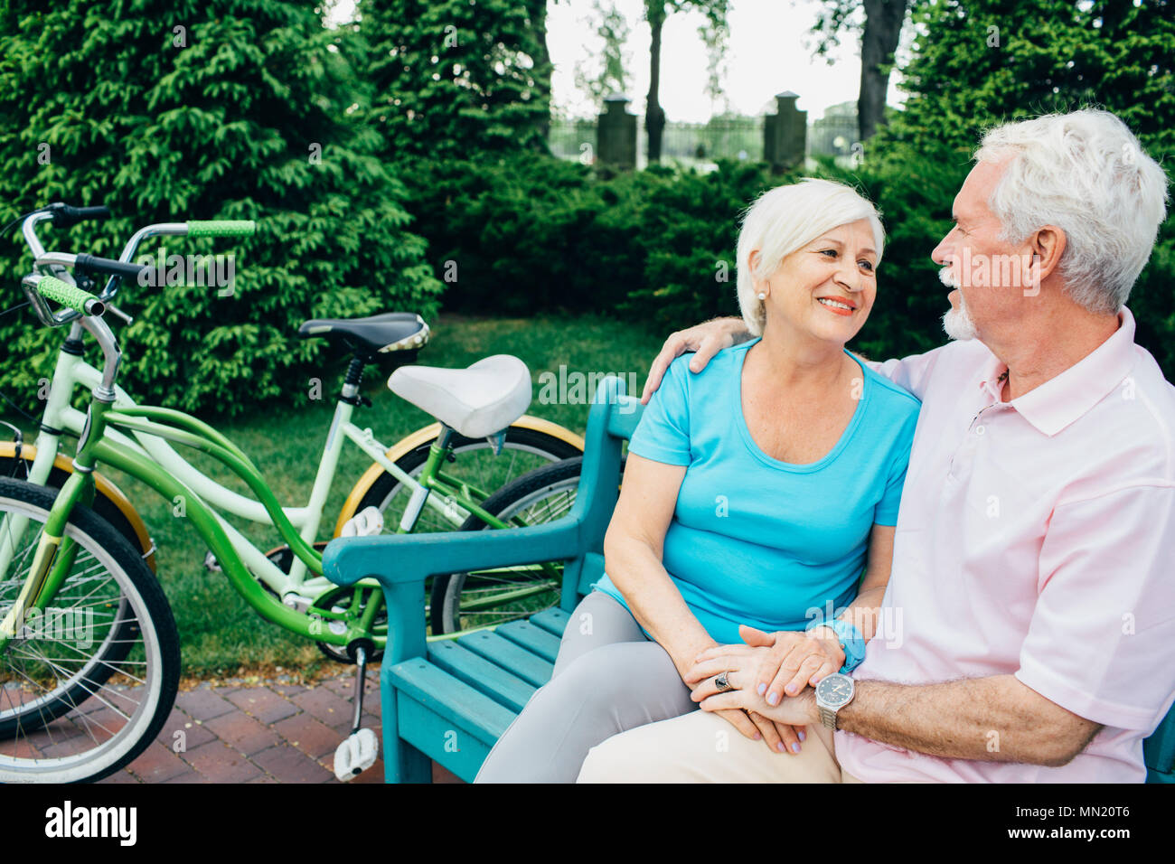 Senior couple relaxing, assis sur parc, après la bicyclette. Une femme et un homme âgés participent activement à la retraite, au repos Banque D'Images