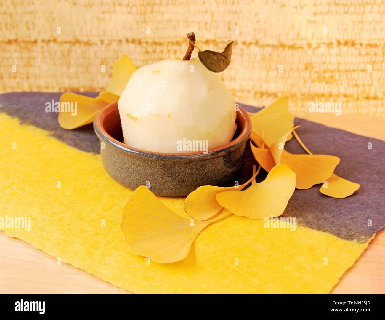 Des fruits épluchés dans un petit plat avec Jaune automne feuilles de ginkgo sur papier texturé avec copie espace Banque D'Images