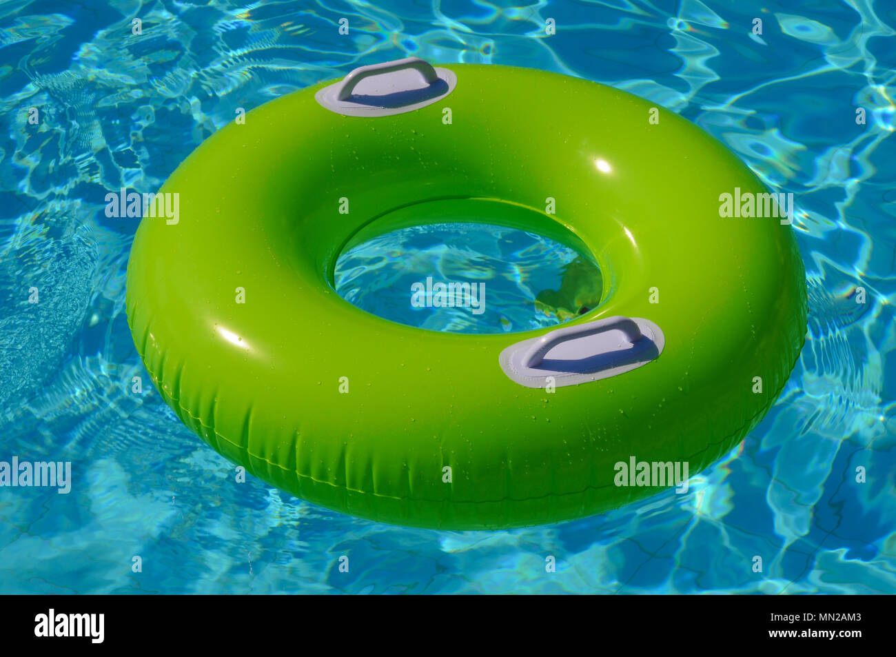 Green life ring flottant sur l'eau bleue dans la piscine Banque D'Images