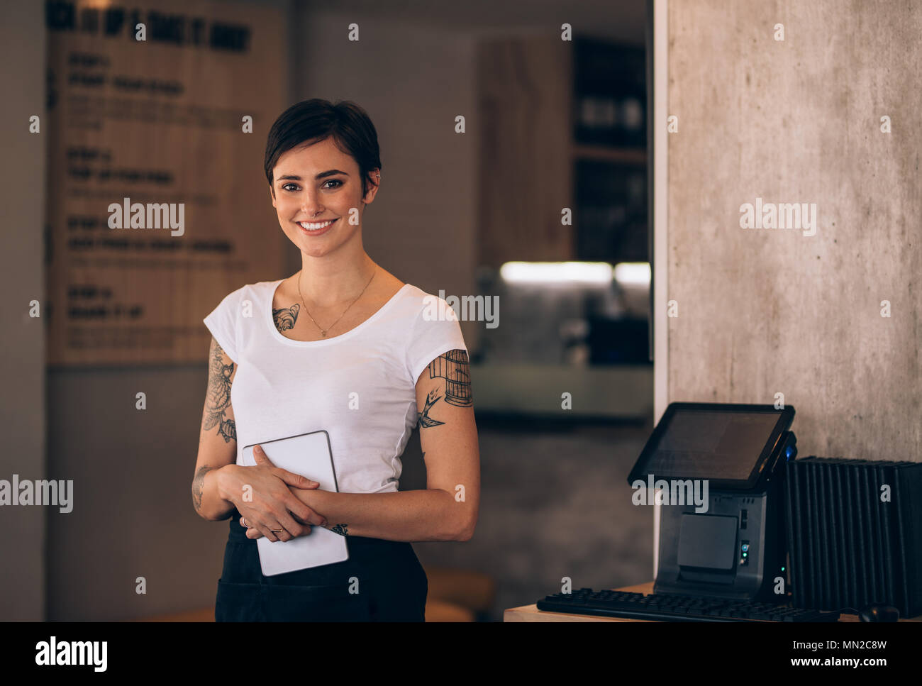 Portrait de belle jeune femme debout dans un café avec une tablette numérique. Serveuse femme travaillant dans un restaurant. Banque D'Images