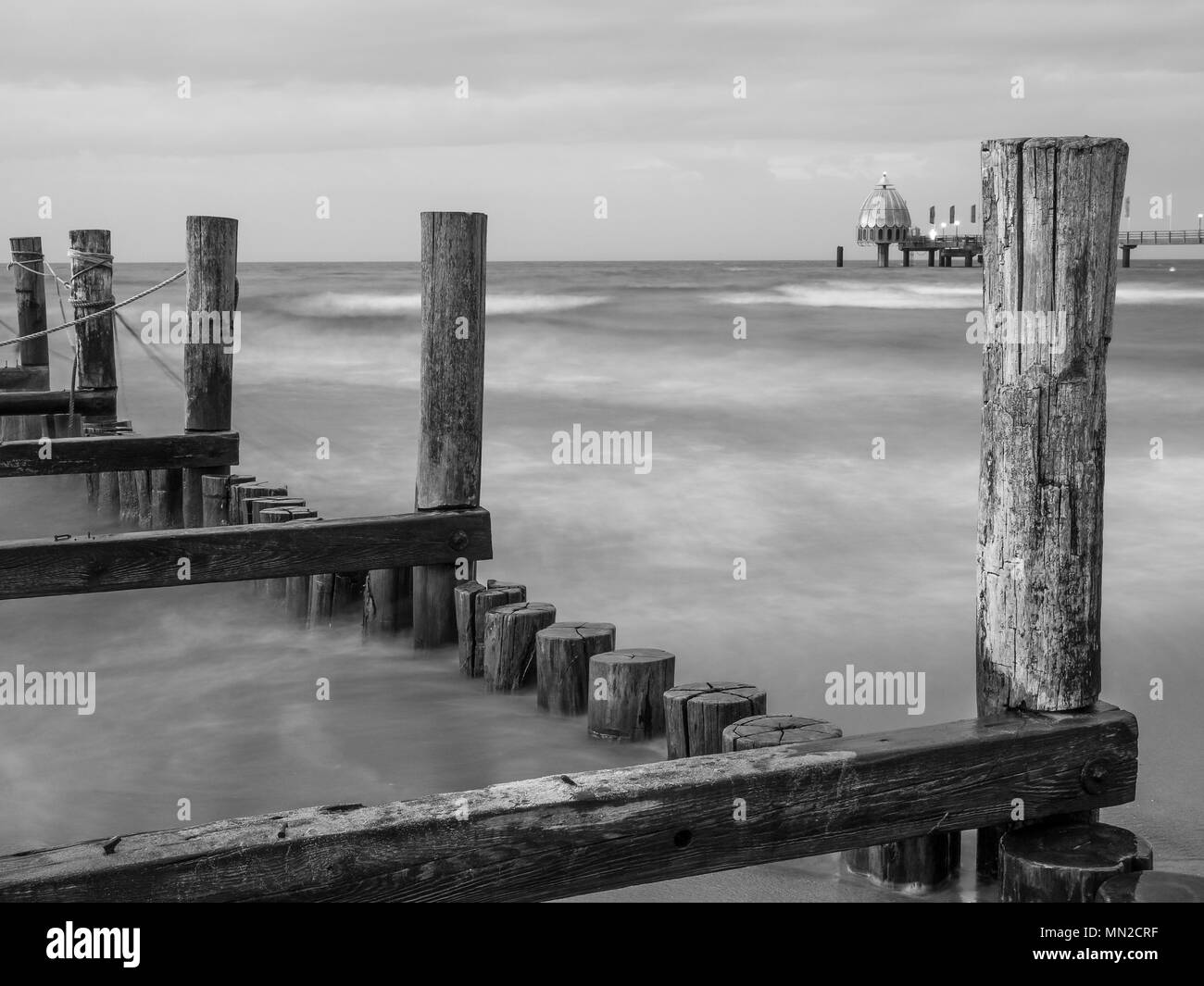 Les brise-lames dans la mer Baltique à Zingst avec pier en arrière-plan, monochrome Banque D'Images