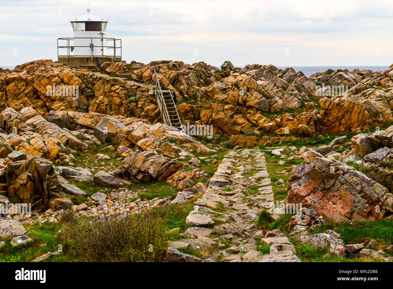 La réserve naturelle de Kullaberg de l'ouest, la Suède - le petit phare blanc Kullen west à la fin d'une falaise côtière par la mer. Banque D'Images