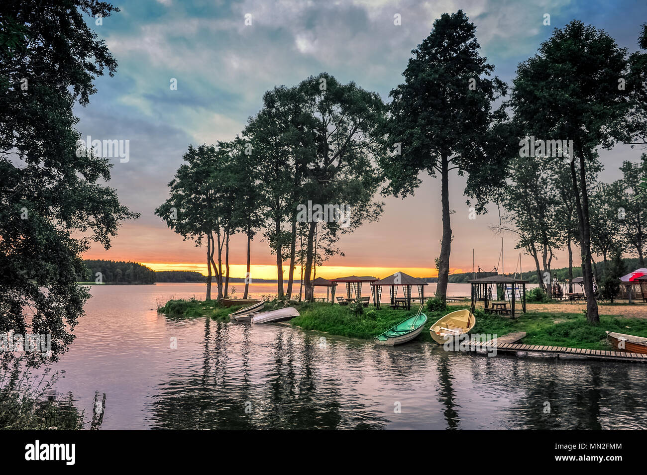 Vue sur le port de pêche du lac avec des bateaux en stationnement sur la rive pendant le coucher du soleil. Banque D'Images
