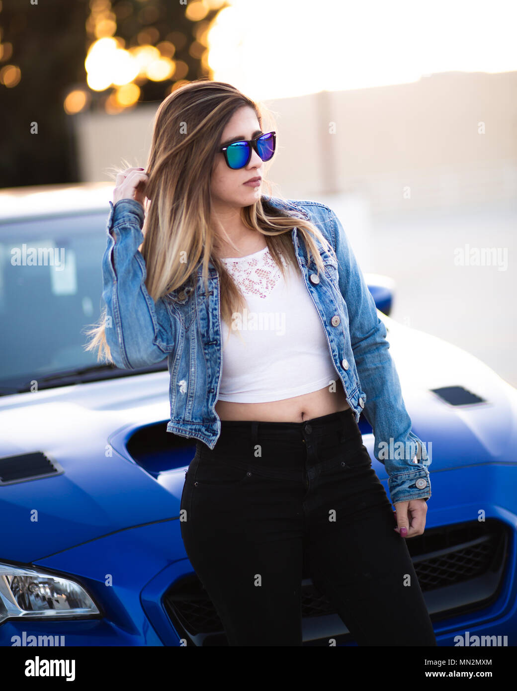 Jeune belle latina avec des lunettes pour le coucher du soleil avec sa  voiture Photo Stock - Alamy