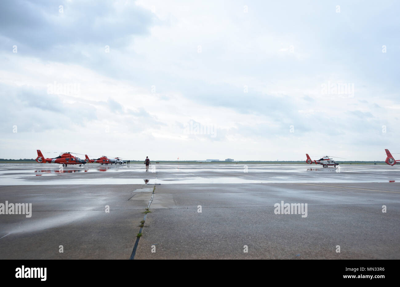 Un nageur de sauvetage de la Garde côtière de promenades à travers les rangées d'hélicoptères à Air Station Houston avant son déploiement dans le cadre d'une mission de sauvetage Le 27 août 2017. Garde côtière canadienne, la Garde nationale aérienne du Texas, des douanes et de la protection des frontières et d'autres organismes fédéraux, d'état et agences locales ont mené des opérations de sauvetage en milieu urbain dans la grande région de Houston depuis le samedi. (U.S. Photo de la Garde côtière canadienne par le maître de 3e classe/Zilnicki Corinne libéré) Banque D'Images