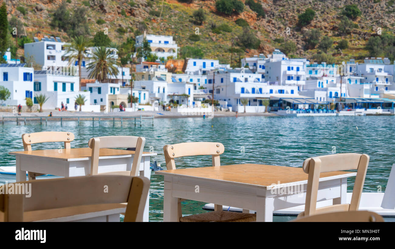 Tables de restaurant avec vue sur le village pittoresque de Loutro en Crète, Grèce Banque D'Images