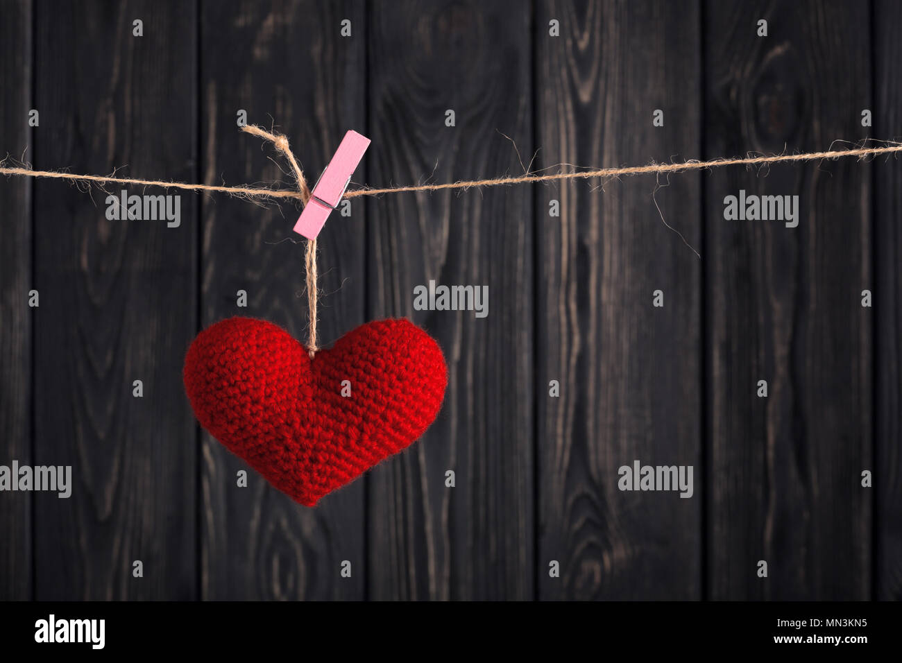 Coeur rouge fait main accroché sur corde avec clothespin gris foncé sur fond de bois. Happy Valentine's Day celebration. Concept Love message Banque D'Images
