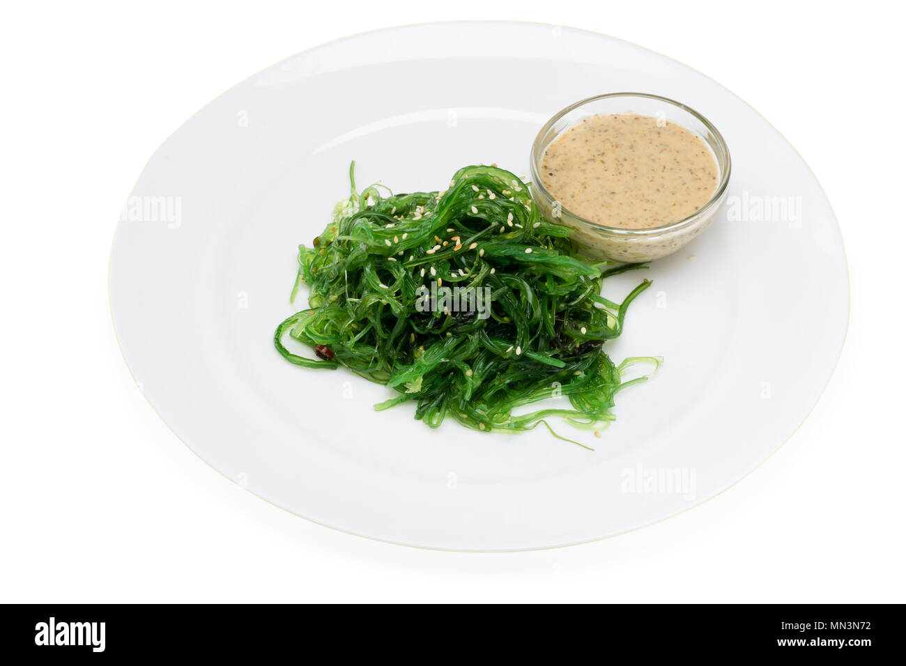 Salade de chou de mer, de sésame et de la sauce blanche sur une plaque sur un fond blanc Banque D'Images