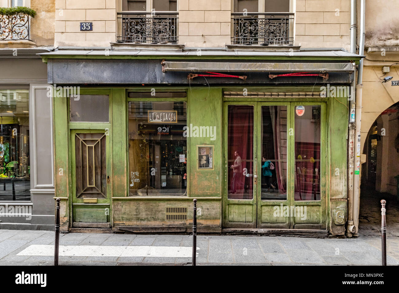 Deux personnes reflète dans les fenêtres de les etages d'un bar un bar discret avec un extérieur vert pâle au coeur du Marais , Paris , France Banque D'Images
