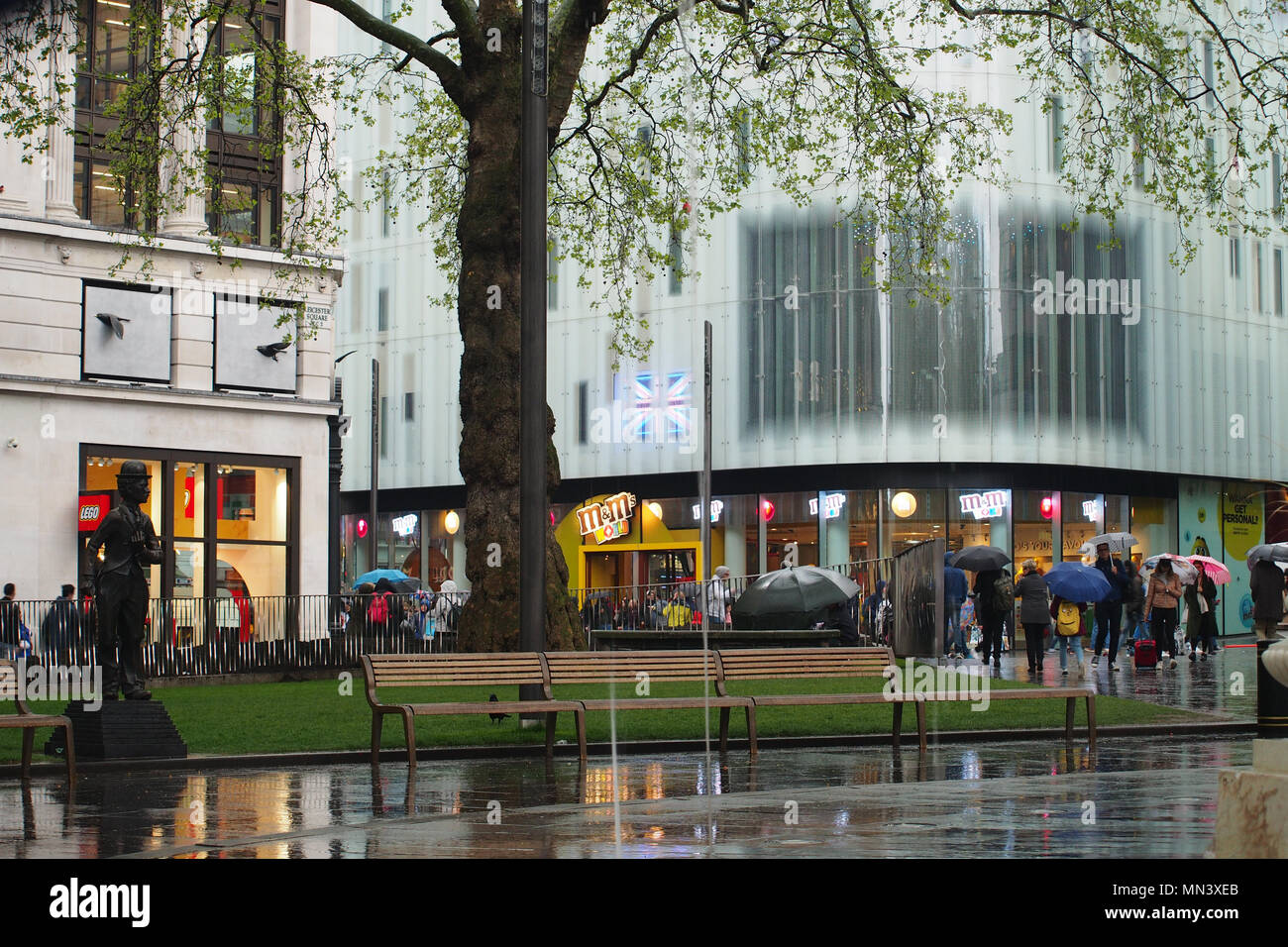 Vue de Leicester Square, Londres à l'état humide, jour d'hiver avec les piétons, les touristes et les visiteurs de parasols et de la statue de Charlie Chaplin Banque D'Images