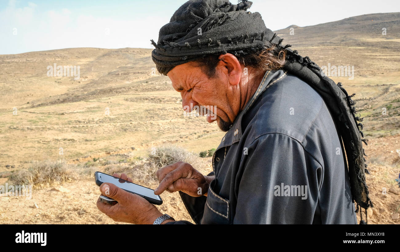 Un bédouin utiliser un smartphone dans un paysage sec Banque D'Images