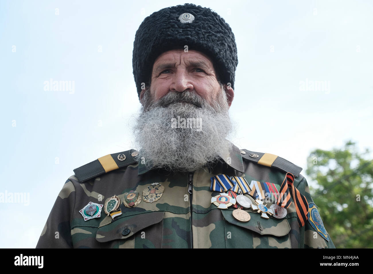Un vétéran portant un chapeau Ushanka en fourrure de trappeur cosaque avec des médailles épinglées dans son manteau militaire posant pendant le jour de la victoire le 9 mai qui commémore la victoire de l'Union soviétique sur l'Allemagne nazie dans le centre de Tiraspol la capitale de Pridnestrovie, officiellement connue sous le nom de République moldave Pridnestrovienne PMR et également appelée Transnistrie depuis 1992 un État sécessionnaire enclavé internationalement reconnu comme faisant partie de Moldave Banque D'Images