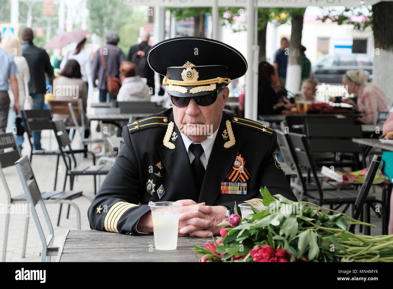 Un vétéran militaire de la marine soviétique portant un uniforme avec de nombreuses médailles et décorations et le ruban de Saint George symbole de la mémoire du peuple soviétique qui a combattu dans la Grande Guerre patriotique (WW II) et a été adopté par les nationalistes russes épinglés dans son manteau militaire se trouve dans un café nommé Mafia Cafe dans le centre de Tiraspol la capitale de Pridnestrovie, officiellement connu sous le nom de République moldave Pridnestrovienne PMR et également appelé Transnistrie depuis 1992 un État sécessionniste enclavé internationalement reconnu comme faisant partie de la Moldavie Banque D'Images