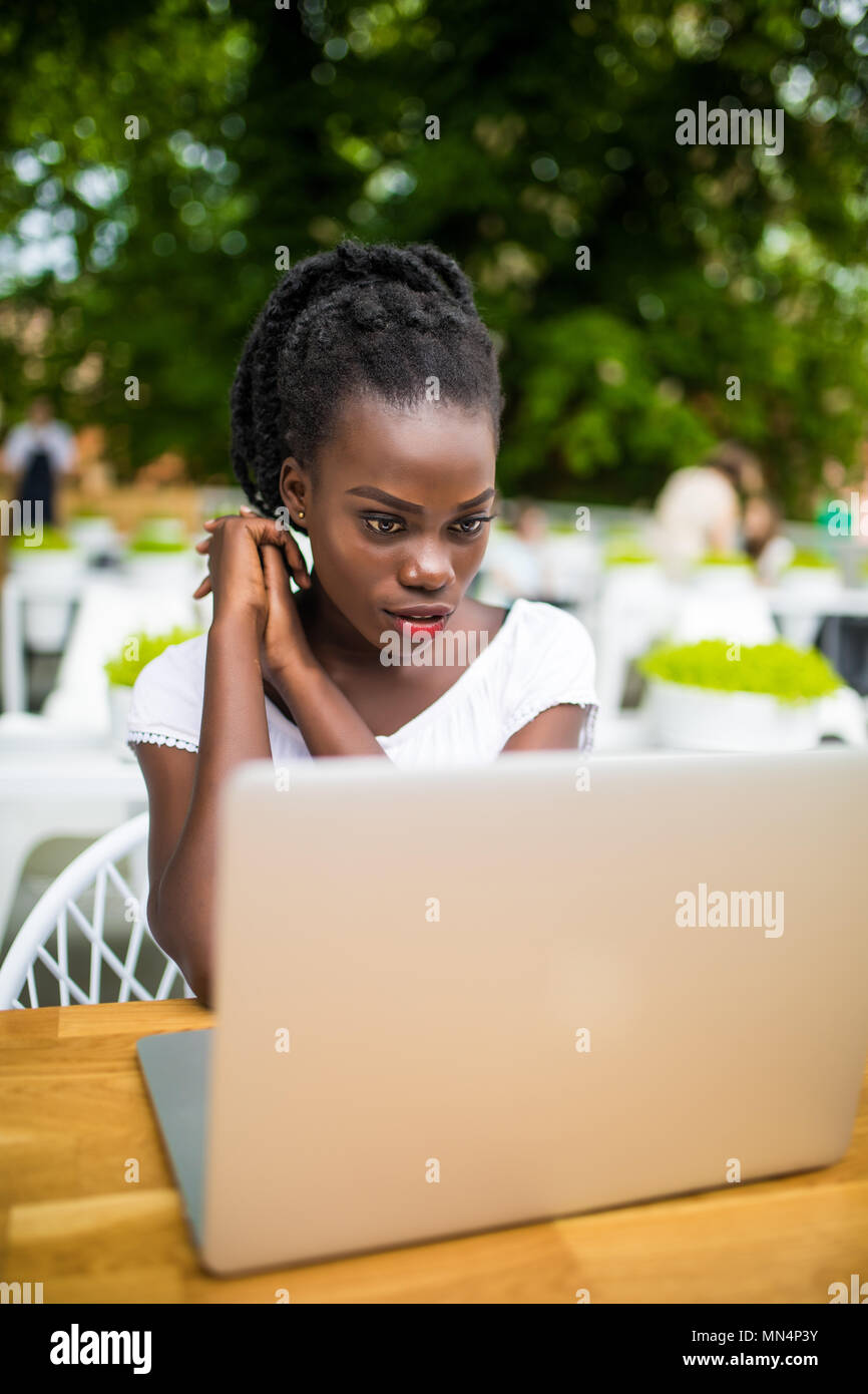 Les jeunes afro-américain black female freelancer travailler avec digital tablet outdoors dans street cafe sur une journée ensoleillée. Banque D'Images
