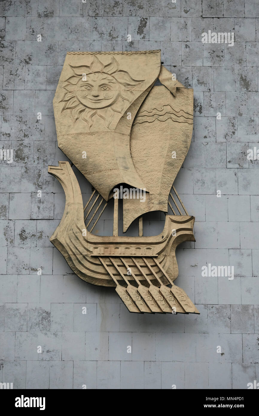 A un bas-relief représentant un voilier stylisé avec un soleil sur sa voile un symbole commun dans l'art soviétique, représentant souvent des thèmes d'espoir, de progrès et de liberté à la façade d'un bâtiment déserté sur la rive du Dniestr dans la ville de Bender nom officiel de facto Bendery in Pridnestrovie, officiellement connu sous le nom de République moldave Pridnestrovienne et également appelé Transnistrie depuis 1992 un État sécessionniste enclavé internationalement reconnu comme faisant partie de Moldavie Banque D'Images
