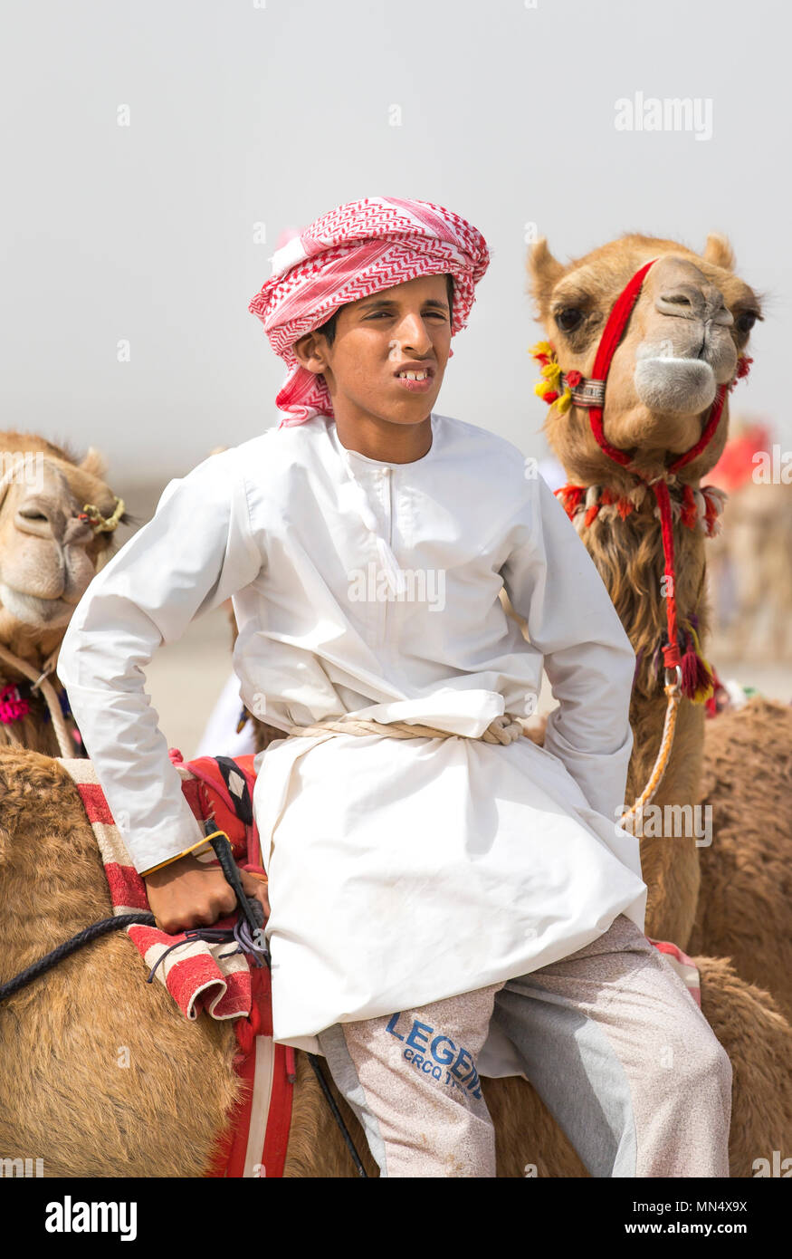 Ibri, Oman, le 28 avril 2018 : kid bédouine avec ses chameaux sur une campagne d'Oman Banque D'Images