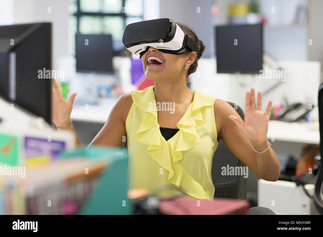 Femme d'enthousiaste à l'aide du simulateur de réalité virtuelle lunettes dans office Banque D'Images