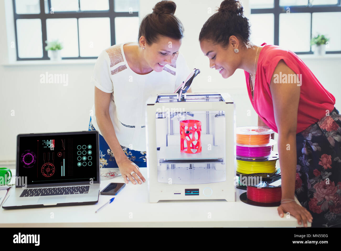 Les concepteurs de femme regardant imprimante 3D in office Banque D'Images