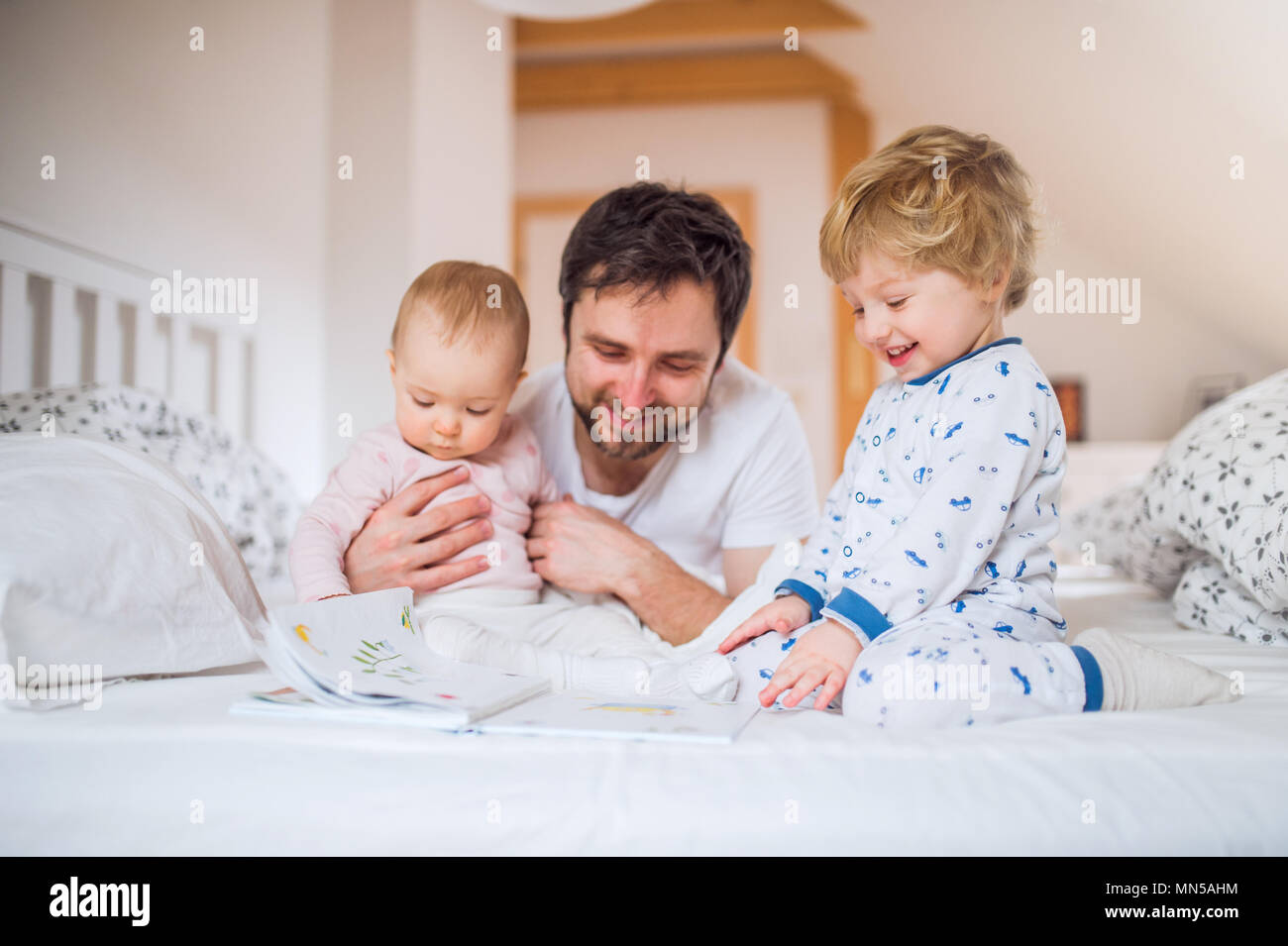 Beau père avec enfant dans la chambre des enfants à la maison, lire des histoires au coucher. Le congé de paternité. Banque D'Images