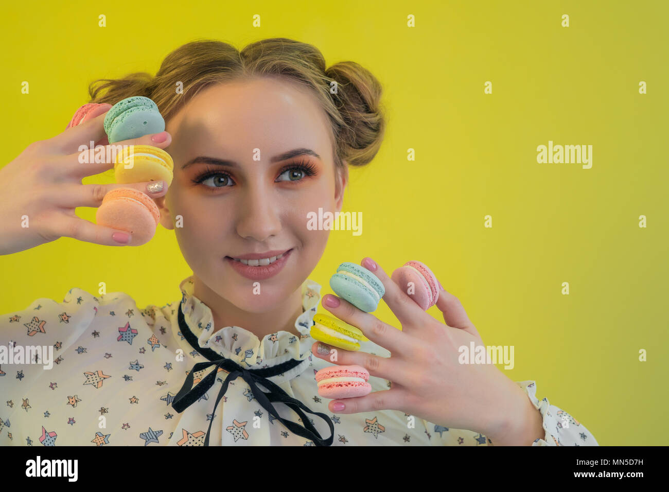 Beau modèle professionnel avec des macarons multicolores holding maquillage Banque D'Images
