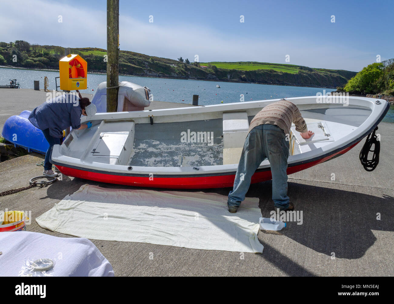 Un couple painting la couche de peinture blanche sur la coque en fibre de  verre d'un bateau en fibre de verre, à l'aide de laque marine Photo Stock -  Alamy