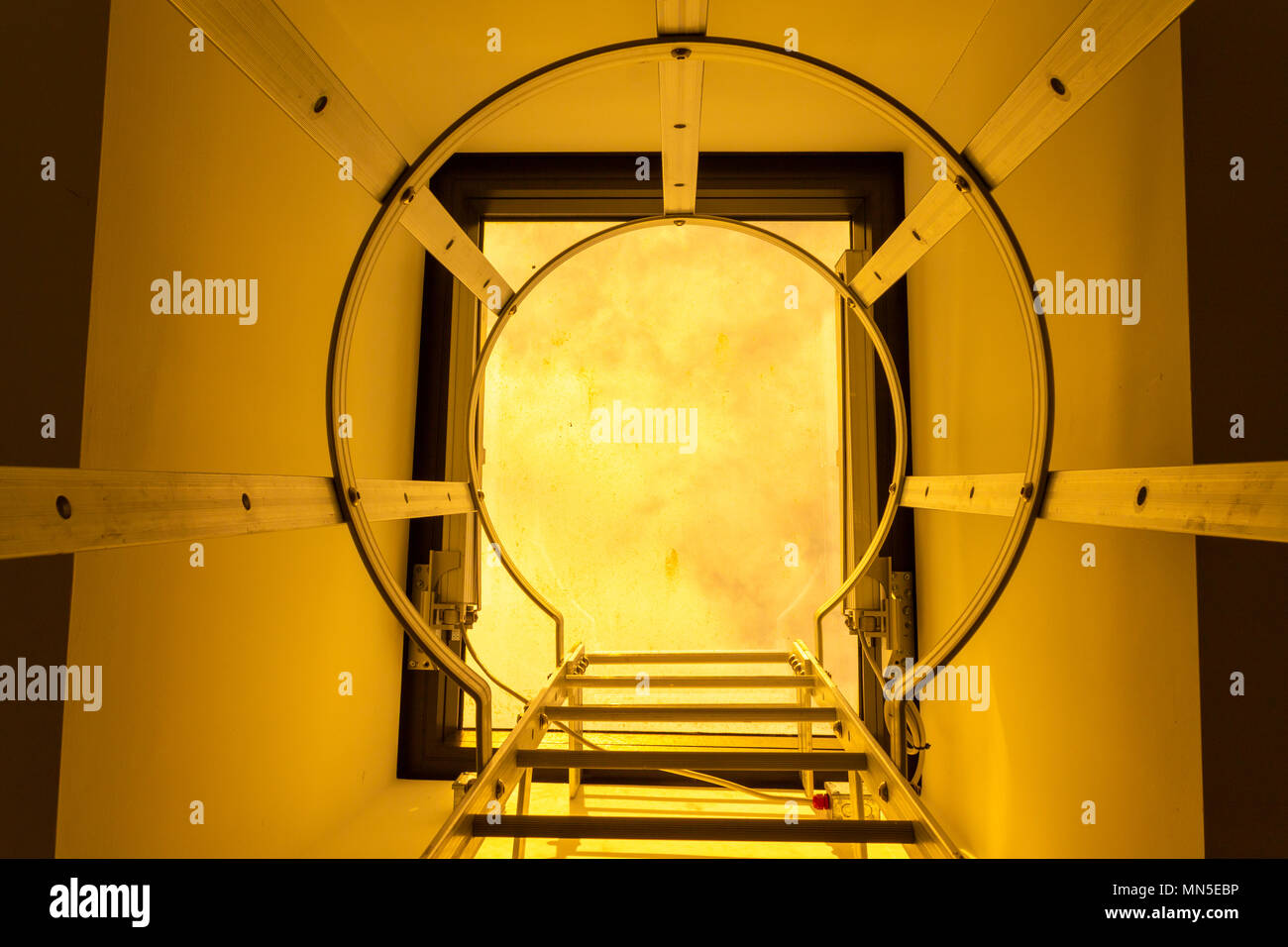 Articles de bain en acier menant sur un toit, avec un couvercle transparent en plexiglas laissant le coucher du soleil en lumière. Banque D'Images