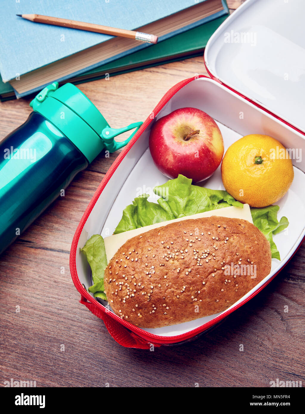 Boîte à lunch saine avec sandwich de pain de blé entier, fruits frais, et une bouteille d'eau sur un bureau en bois. Concept de l'école pause déjeuner. Banque D'Images