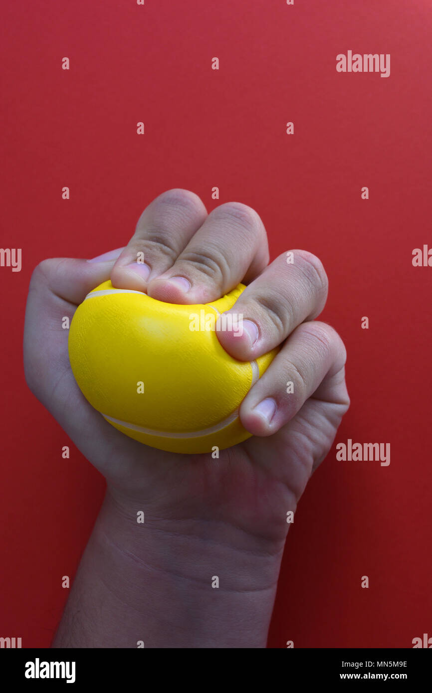 Woman squeezing une balle anti-stress, close-up, sur un fond rouge avec l'exemplaire de l'espace. Banque D'Images