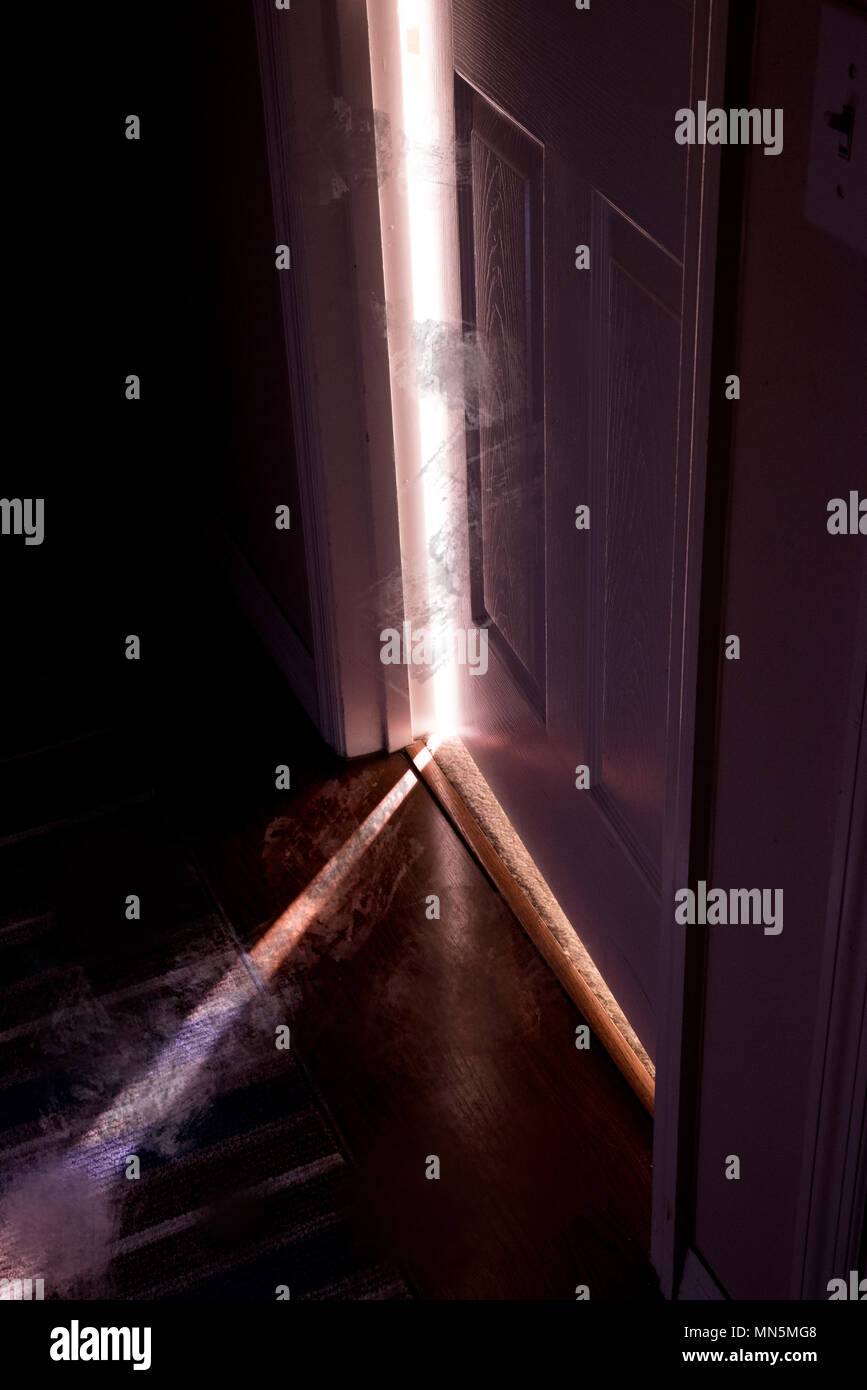 La lumière vive et la fumée s'échapper par une porte légèrement ouverte à l'intérieur de la maison. Banque D'Images