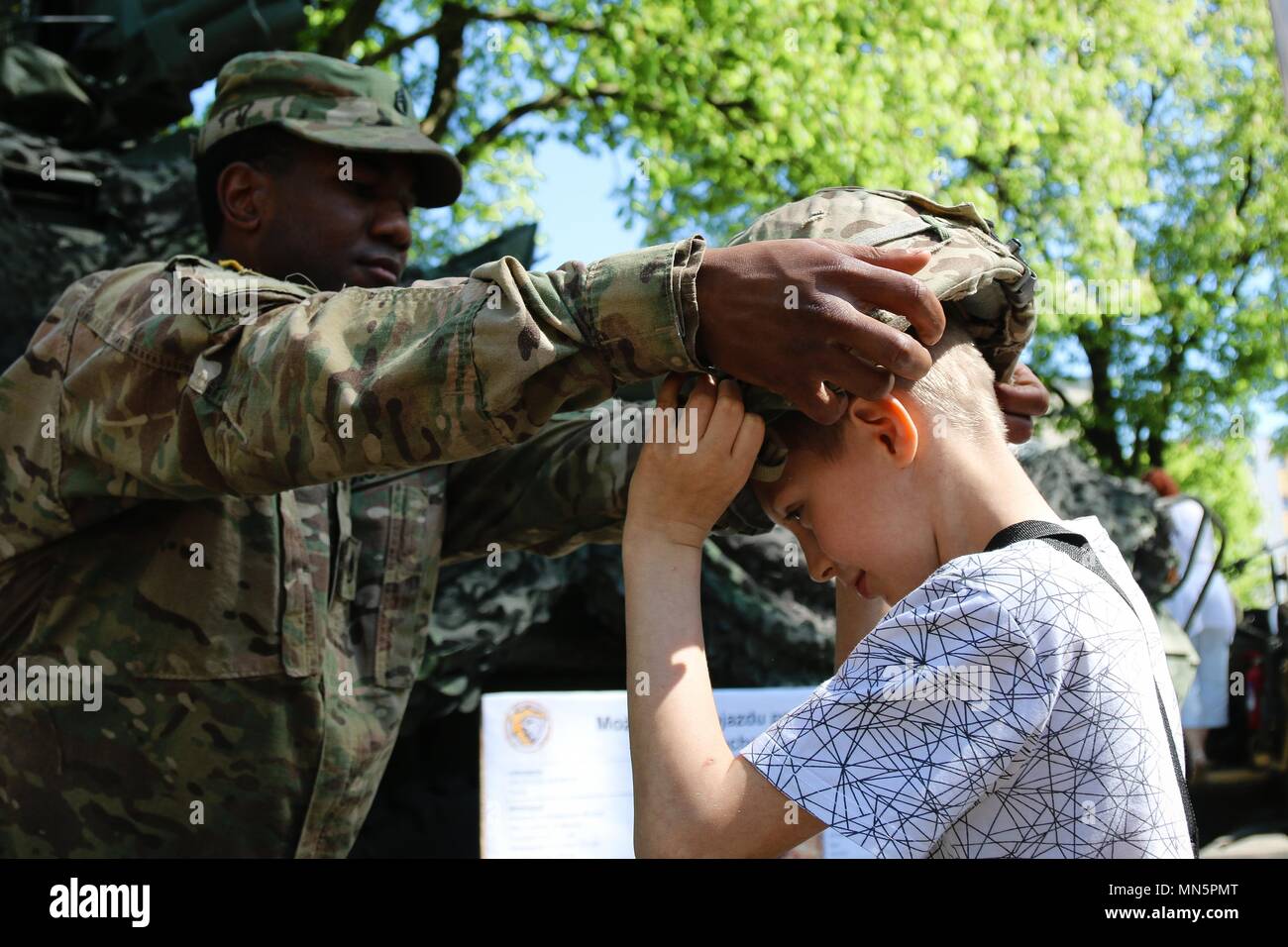 Le sergent de l'armée américaine. Jared Cherry Mettre son casque en Kevlar sur un garçon polonais, Gizycko, Pologne, mai 2018. Image courtoisie de la CPS. Hubert Delany / Battle Group Pologne. () Banque D'Images