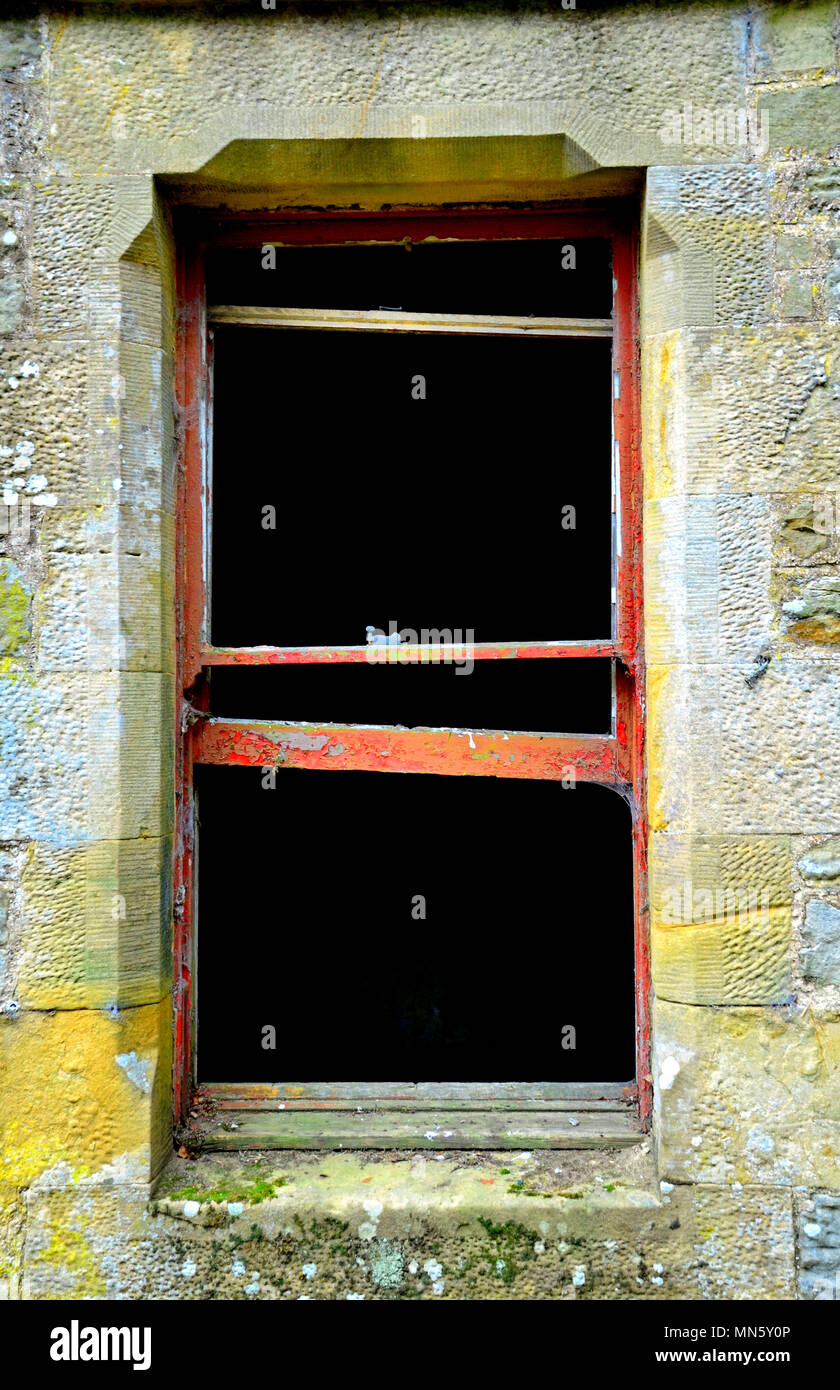 Les cadres de fenêtre en bois en décomposition rouge du bâtiment abandonné Banque D'Images