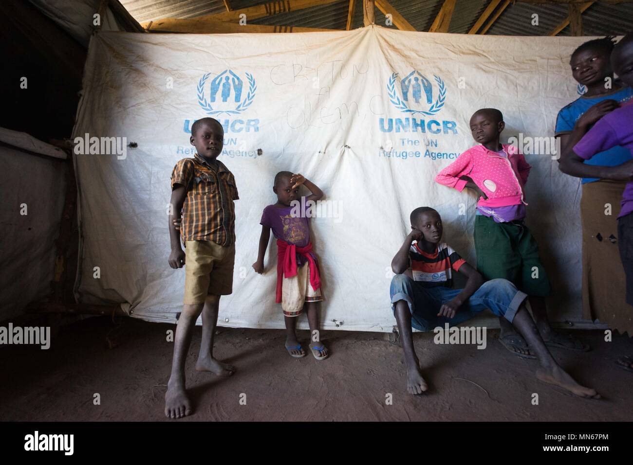 Les jeunes nouvellement arrivés vu les réfugiés sud-soudanais en face d'un logo du HCR. Kuluba le centre d'accueil des réfugiés est l'un des nombreux centres d'accueil dans le nord de l'Ouganda spécialement construit pour gérer les centaines de milliers de réfugiés sud-soudanais afflux. Le centre d'accueil est où les réfugiés sont enregistrés par le HCR en tant que réfugiés officiellement et qu'ils sont rester ici pendant 24 à 48 heures avant d'être transférée à l'installation des réfugiés plus permanente. Banque D'Images