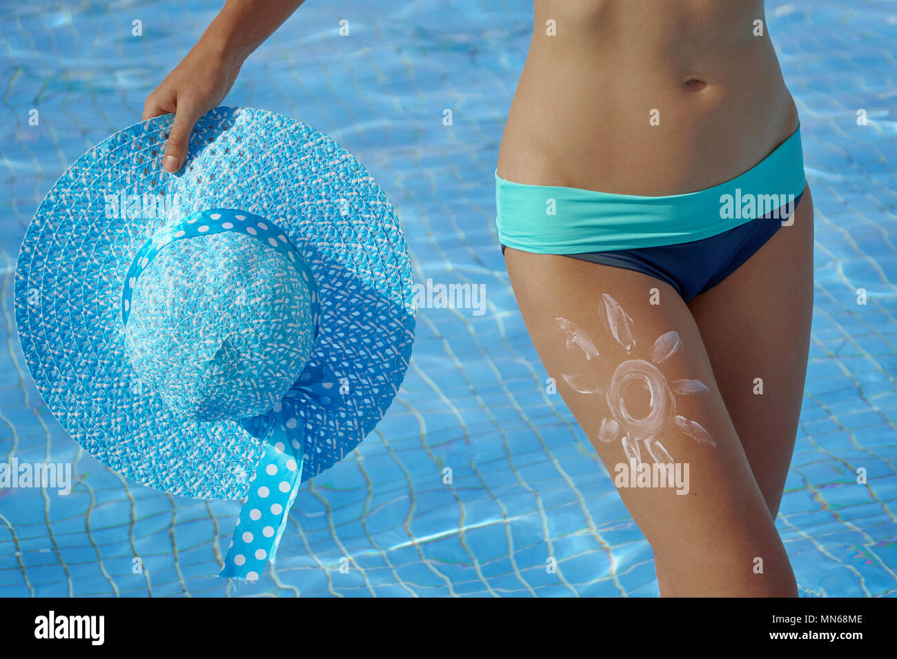 L'écran solaire et de belles jambes féminines dans la piscine de l'image conceptuelle de locations Banque D'Images