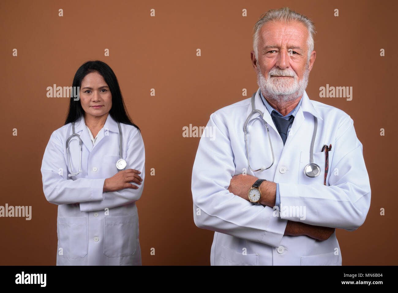 Multi-ethnic couple mature médecins contre fond brun Banque D'Images
