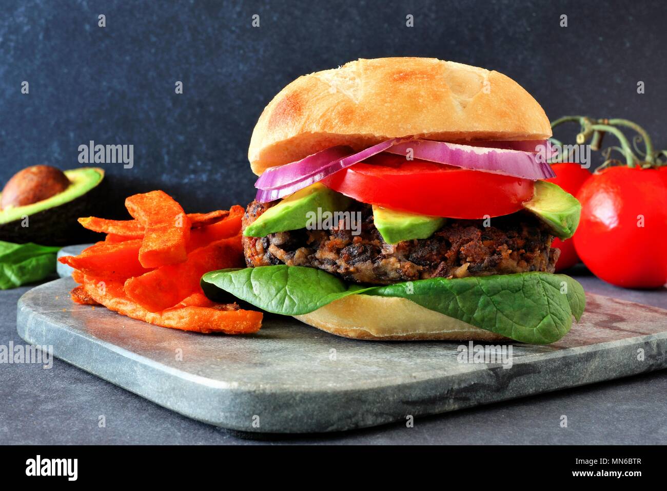 Bean burger végétarien avec de l'avocat, Épinards et pommes de terre frites sur un fond sombre Banque D'Images
