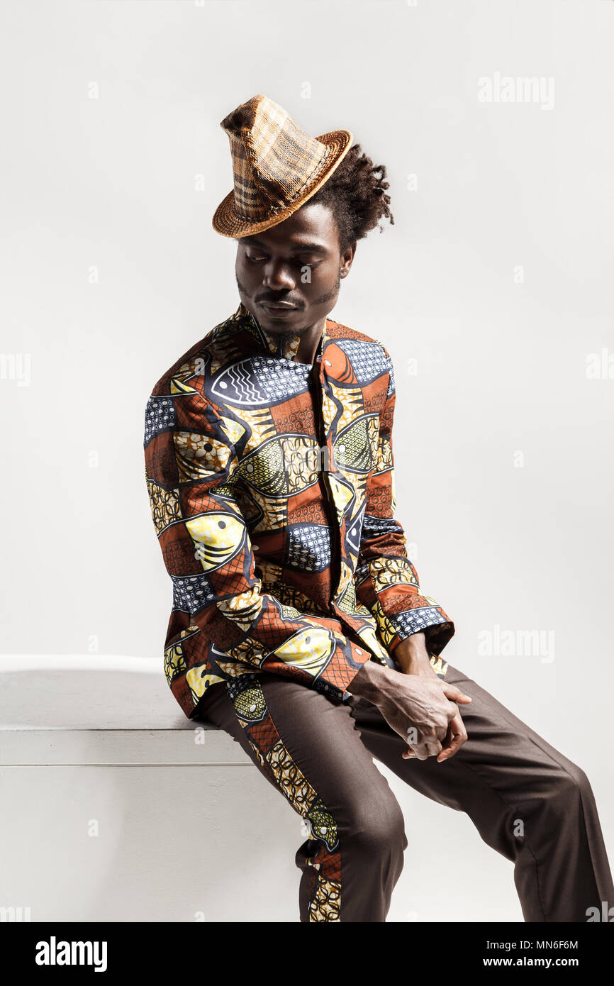 Homme africain en costume national kongo s'asseoir sur coub . Piscine, isolé sur fond gris Banque D'Images