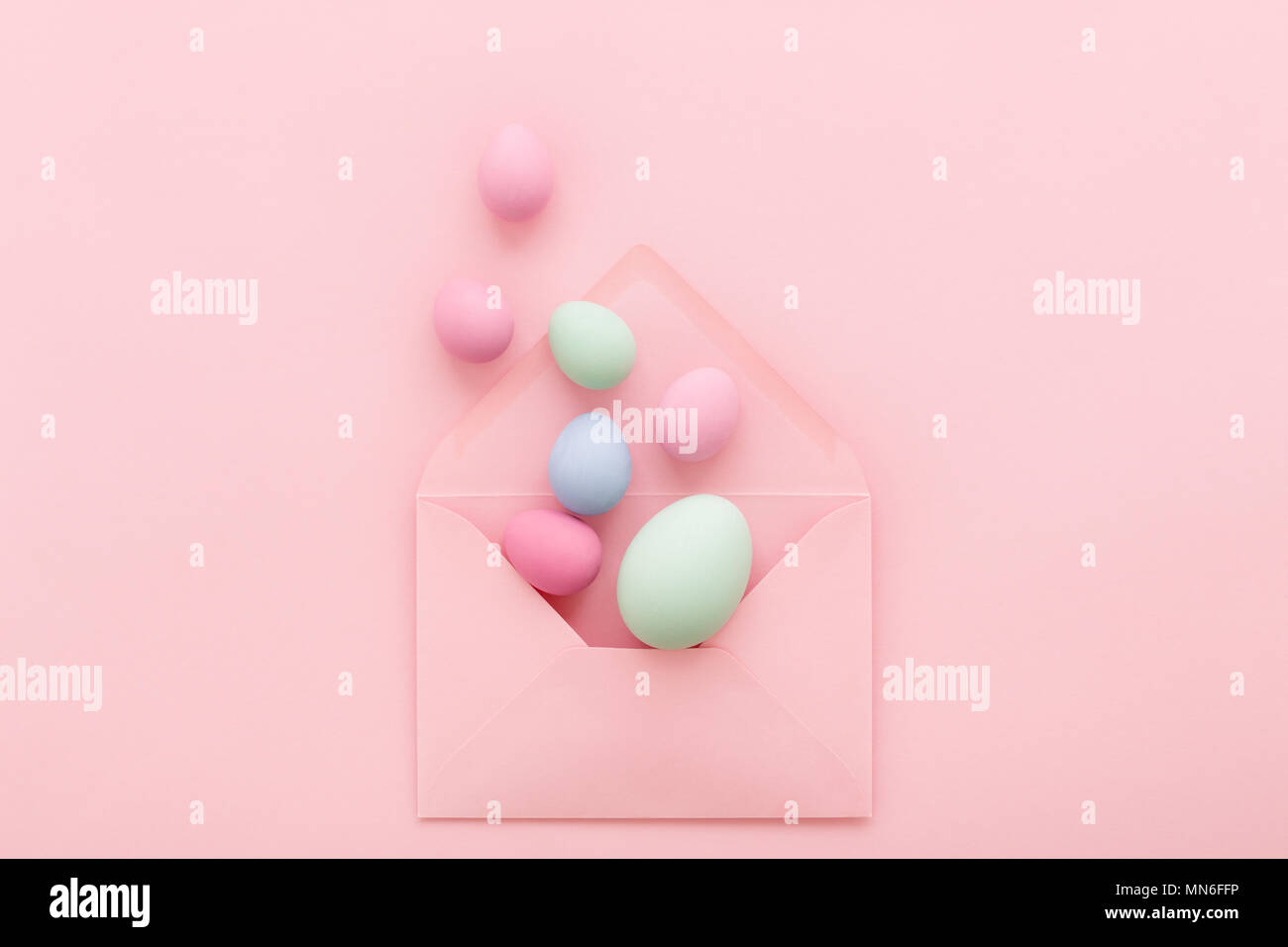 Oeufs de Pâques dans l'enveloppe rose sur fond rose. Bonnes vacances message, concept de la correspondance. Mise à plat, un style minimaliste carte de souhaits Banque D'Images